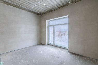 Odanın inşaatı devam ediyor. Duvarları alçılı, zemini beton. Oturma Odası Bölgesi. Geniş