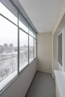 Parlak, kapalı bir balkon, açık pencereler, pürüzsüz duvarlar ve karlı bir şehir manzarası. Temiz hatlar kentsel yaşamı vurgular, sakin kış ayarı ise sakinlik duygusunu artırır.