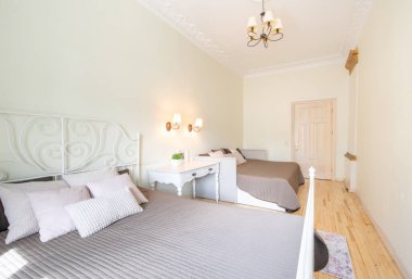 Lüks Ev Klasik Yatak Odası İçi. Büyük boy yatak, beyaz duvarlar ve tavan. Pencereler ve Perde. Eski kahve masası. Arka plandaki kapı. Geniş Açı