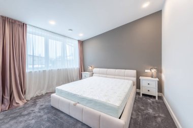 Lüks Ev Yatak Odası İçi. Büyük boy yatak, beyaz duvarlar ve tavan. Pencereler ve Perde. Kahve masası, yerde halı. LED Işık. Geniş Açı