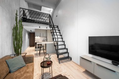 Lüks Çatı Stili Stüdyo Daire Modern Salon Bölgesi, Konforlu Yatak Odası. İnsansız Minimalist Modern İç mimari. Arka planda Büyük Kanepe, Masa, Mutfak Bölgesi. İkinci Katın Merdiveni.