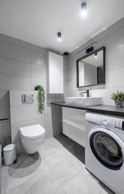 Beyaz Lavabolu Parlak Modern Lüks Ev Banyosu İç Tasarımı. Gri Duvarlar, Ayna ve Musluk döşemeleri. LED ışıkları. Duş Alanı, Isıtıcı, Çamaşır Makinesi. Geniş Açı