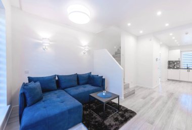 Modern Ev Oturma Odası İçi Açık TV Alanı ve Masa Masası 'nda TV, Mavi Koltuk ve Kahve Masası. Ahşap döşeme, yerde halı. Arka planda mutfak alanı. Geniş Açı