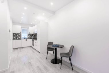 İskandinav Tarzı Konforlu Modern Açık Parlak Mutfak İç mimarisi. Siyah Yemek Kahve Masası. Beyaz Duvar ve Tavan. Geniş Açı