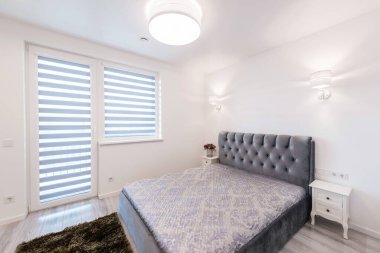 Geniş Ev Yatak Odası İçi Açısı. Büyük boy çift kişilik yatak. Beyaz Duvarlar. Aile Evi. Pencere ve Kapı 'dan Balkona. Yerde halı var. Parlak Güneşli Gün