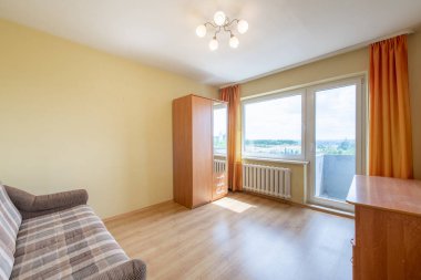 Minimalizm Ev Yatak Odası İçi. Dolap, Hardwood döşemesi. Kanepe. Arka planda ısıtıcı ve pencere var. Ev