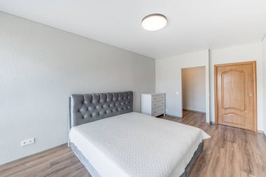 Ev Yatak Odası İçi. Büyük boy çift kişilik yatak, kahverengi tahta çıkış kapısı. Beyaz Duvar ve Tavan. LED Liaght. Dark Hardwood Zemini. Beyaz Çekmeceler. Geniş Açı
