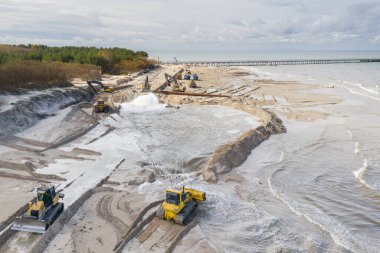 Plaj restorasyonu ve buldozerler. Denizin götürdüğü sahilin yeniden inşası için kazıcıyla birlikte borudan çamur akıyor. Plaj besinleri için çalışmalar devam ediyor. Drone Hava Çekimi