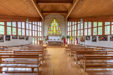İçinde vitray pencereler, ahşap banklar ve sanat bulunan parlak ahşap bir kilise. Litvanya