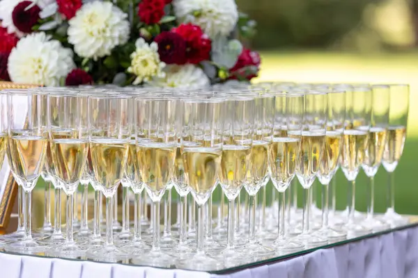 Masada köpüklü şarapla dolu zarif şampanya kadehleri. Düğünler, partiler veya etkinlikler için ideal bir kutlama ortamı.
