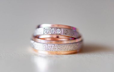 Karmaşık tasarlanmış iki evlilik yüzüğünün detaylı bir yakın çekimi, altın ve gümüş dokular, aşkı ve bağlılığı sembolize eden, evliliği, birliği ve zarif mücevher kavramlarını temsil eden,