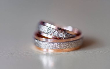 Karmaşık bir şekilde tasarlanmış elmas yüzükler gül altın ve gümüşle süslenmiş lüks ve bağlılık göstergesi. Karmaşık detaylar aşkı, güzelliği ve zamansızlığı vurgular.