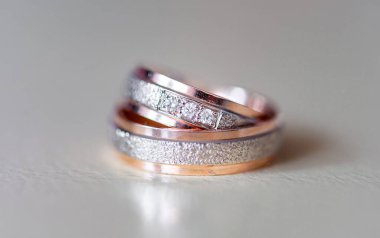 Karmaşık bir şekilde tasarlanmış elmas yüzükler gül altın ve gümüşle süslenmiş lüks ve bağlılık göstergesi. Karmaşık detaylar aşkı, güzelliği ve zamansızlığı vurgular.