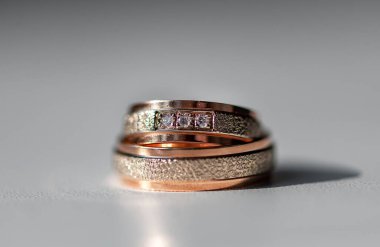 Karmaşık bir şekilde tasarlanmış elmas yüzükler gül altın ve gümüşle süslenmiş lüks ve bağlılık göstergesi. Karmaşık detaylar aşkı, güzelliği ve zamansızlığı vurgular.