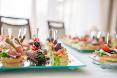 Şık bir ortamda cam tepside sunulan çeşitli aperatiflerin yakın çekimi yemek sanatını ve rafine yemek konseptini vurguluyor..