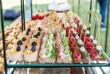 Taze hazırlanmış aperatifler, lezzetli kanepeler, süslü abur cuburlar, ve sanatsal olarak hazırlanmış ısırıklar yemek servisi için çok katlı stantlar..