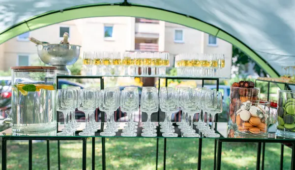 Estetik olarak düzenlenmiş bir açık hava içecek istasyonu. Bardaklar, meyveli su, badem kurabiyeleri ve içecekler. Kutlamalar ve toplantılar için mükemmel bir bahçe ortamı..