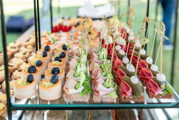 Taze hazırlanmış aperatifler, lezzetli kanepeler, süslü abur cuburlar, ve sanatsal olarak hazırlanmış ısırıklar yemek servisi için çok katlı stantlar..
