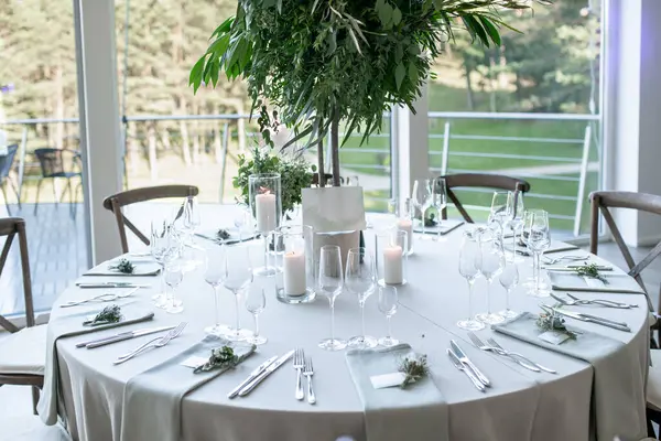 Çok güzel dekore edilmiş düğün masası zarif sofra takımı, mum ışığı atmosferi ve çarpıcı bir yeşillik süsü, sofistike bir atmosfer ve kutlama havası yayıyor.