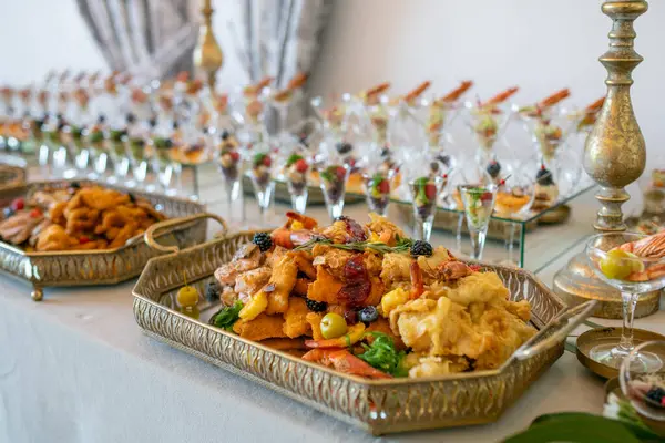 Şatafatlı büfe, gurme kızartmaları, deniz mahsulleri taze meyveler ve zarif aperatifler sunar. Sofistike bir düzende servis edilir. Güzel süslenmiş bir mekanda parlak detaylarla yakalanır.