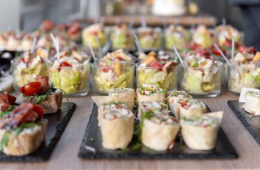 Çeşitli düğün aperatifleri, ambalajlar ve salatalar da dahil, tepsilerde yiyecek ve içecekler için güzel bir şekilde sergileniyor. Etkinlikler, partiler ya da kutlamalar için mükemmel, gurme yemek sunumu