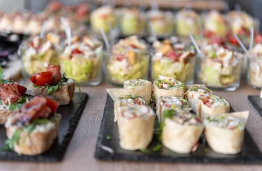 Çeşitli düğün aperatifleri, ambalajlar ve salatalar da dahil, tepsilerde yiyecek ve içecekler için güzel bir şekilde sergileniyor. Etkinlikler, partiler ya da kutlamalar için mükemmel, gurme yemek sunumu