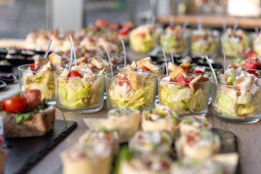 Çeşitli düğün aperatifleri, ambalajlar ve salatalar da dahil, tepsilerde yiyecek ve içecekler için güzel bir şekilde sergileniyor. Etkinlikler, partiler ya da kutlamalar için mükemmel, gurme yemek sunumu