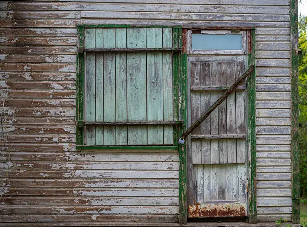 Kırsal ahşap bina cephesinde eskimiş bir kapı ve kepenkli bir pencere, eşsiz dokular ve yaşlanmış karakterler sergileniyor. Kusursuz bir şekilde, kırsal alanda klasik bir çevresel cazibeyi resmediyor.