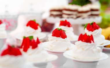 Çilek ve kremayla süslenmiş lezzetli bir krema seçimi. Şenlikli bir ortamda zarif tabaklar halinde. Parti ve kutlamalar için mükemmel.