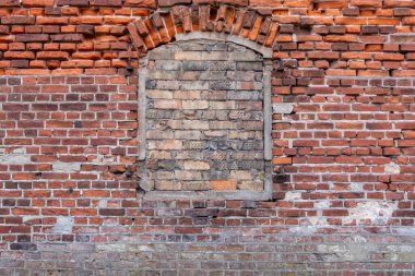 Tuğla şeklinde bir pencereye sahip kırmızı tuğla duvar, eşsiz tarihsel mimari ve kentsel bozulma desenlerini sergiliyor, klasik cazibeyle ilgili yaratıcı veya mimari projeler için mükemmel.