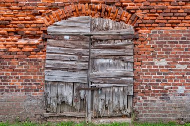 Kırsal ahşap panjurlar yıpranmış tuğla bir duvarda, tarihi mimari ve canlı dokular sergileniyor..
