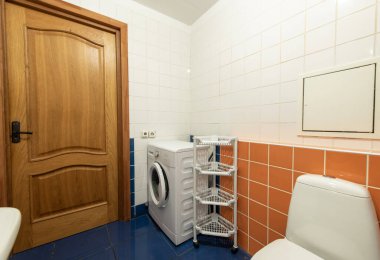 Parlak ve temiz banyo içinde bir çamaşır makinesi, kompakt raf, ve canlı fayanslı duvarlar, kompakt yaşam alanlarında pratik tasarım sergilemek için mükemmel..