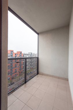 Modern bir apartmandaki minimalist balkon bulutlu hava estetiği altında kentsel manzara arkaplanı sergiliyor.