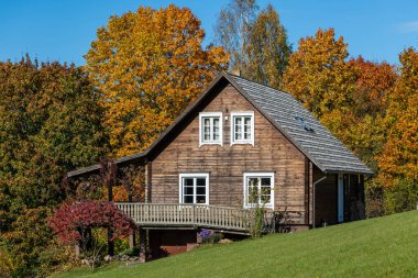 Uçsuz bucaksız ahşap bir ev. Geniş bir balkon. Renkli bir sonbahar ormanı düzenine yerleşmiş..