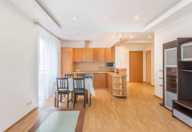 Çağdaş ahşap dolaplar, geniş bir yerleşim yeri ve geniş pencerelerden bol miktarda doğal ışık içeren parlak ve düzenli bir ev mutfağı ve yemek odası.