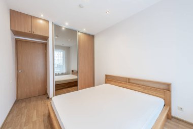 Parlak ve modern yatak odası ahşap mobilyalar, büyük bir ayna, ve geniş doğal ışık bir pencereden içeri akıyor katıksız perdelerle süslenmiş, huzurlu ve misafirperver bir atmosfer yaratıyor..