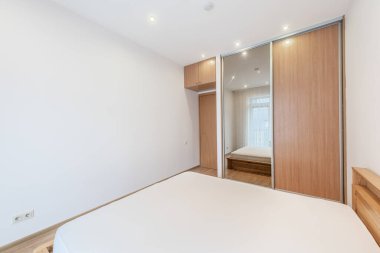 Parlak ve düzenli yatak odası, minimalist tasarım, ahşap mobilyalar, nötr renkler ve rahat atmosfer. İç tasarım ilhamı veya emlak sergisi için ideal.