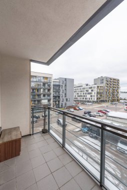 Camdan korkulukların ve kentsel konut binalarının manzaralı modern ev dairesi temiz minimalist estetiği vurguluyor.