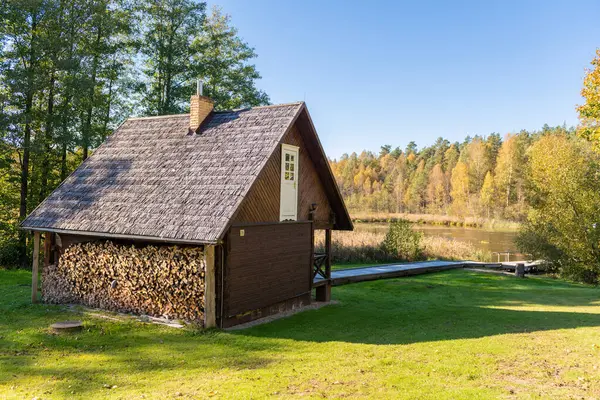 Bir sonbahar ormanı sahnesinin ortasında sakin bir göl kenarında geleneksel bir tasarımı olan ahşap kulübe saunası doğanın güzelliğini gözler önüne seriyor ve barışçıl bir geri çekilmeye davet ediyor.