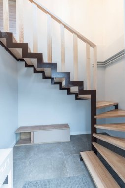 Modern geometrik elementlerin yer aldığı şık ahşap merdiven, çağdaş bir mimari ve iç tasarım estetiği sergileyen, parlak ve minimal bir iç mekanla tamamlanmış..