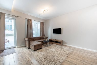 Modern dekorun, rahat mobilyaların ve perdeli büyük pencerelerin olduğu zarif bir oturma odası. Rahatlama, eğlence ve sosyalleşme için tasarlanmış parlak bir alan