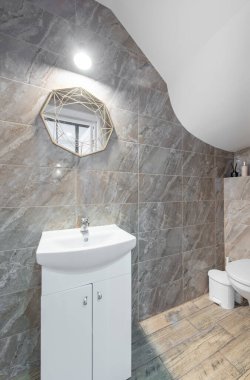 Modern dekor, geometrik ayna, temiz fayanslar ve depolanmış güncel bir lavabo, ferahlatıcı ve işlevsel bir atmosfer yaratıyor..