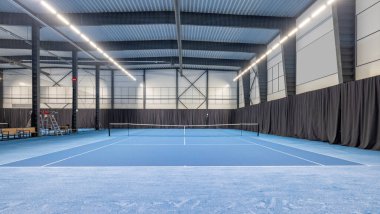 Canlı, mavi oyun yüzeyi, modern tesisleri ve bol ışıklandırması olan geniş bir tenis kortu. Spor müsabakaları, antrenmanlar ve eğlence amaçlı tenis için mükemmel..