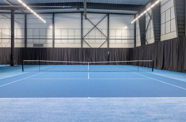 Canlı, mavi oyun yüzeyi, modern tesisleri ve bol ışıklandırması olan geniş bir tenis kortu. Spor müsabakaları, antrenmanlar ve eğlence amaçlı tenis için mükemmel..