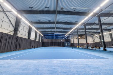 Canlı, mavi oyun yüzeyi, modern tesisleri ve bol ışıklandırması olan geniş bir tenis kortu. Spor müsabakaları, antrenmanlar ve eğlence amaçlı tenis için mükemmel..