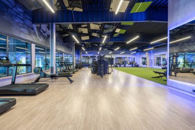 A contemporary gym with state-of-the-art fitness equipment, treadmills, exercise machines, and open space areas. Brightly lit and well-designed for various fitness and workout activities