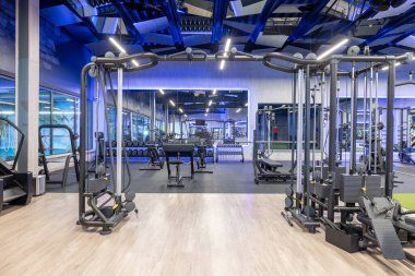 Interior of a contemporary fitness center with advanced gym equipment, elegant flooring, and ambient lighting, emphasizing modernity, health, and fitness.