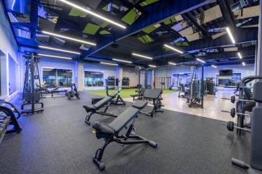 Bright and contemporary gym interior featuring various fitness equipment, weights, and an open layout with motivational ambiance. Perfect for exercising, personal training, and achieving health goals
