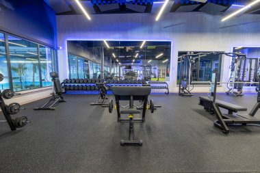 Bright and spacious gym interior featuring modern equipment, mirrors, fitness machines, and neon lighting, designed to promote a motivating and enjoyable workout atmosphere for fitness enthusiasts