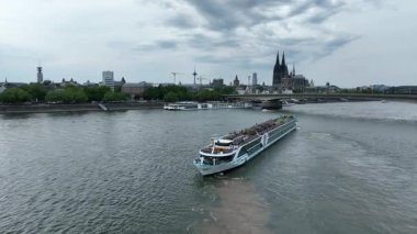 Cruise Ship Ferry Boat in Cologne City, Rhine River. Cathedral and Bridge in Background. Germany, Drone, 4k